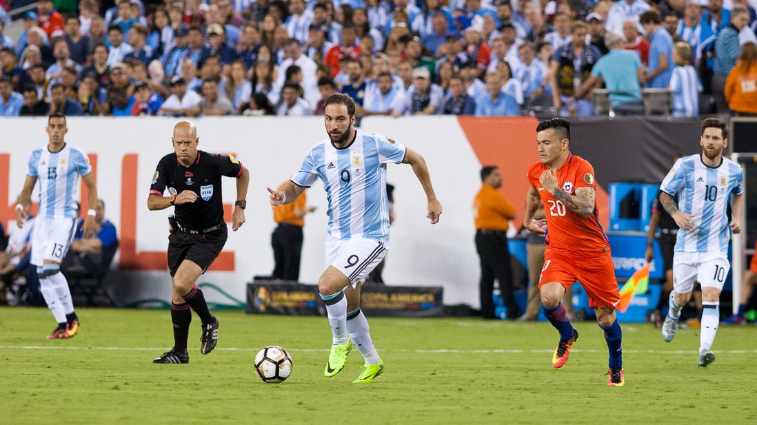Argentina's Gonzalo Higuain (9) attacks while other players and referee Heber Lopes give chase.